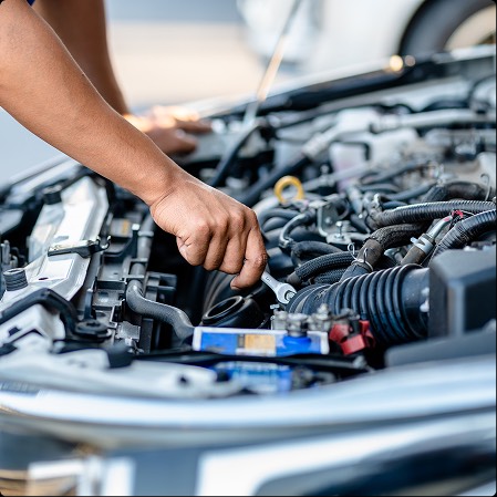 Mano di un meccanico che utilizza una chiave per lavorare su un motore di un'auto, con particolari dettagli del motore visibili.