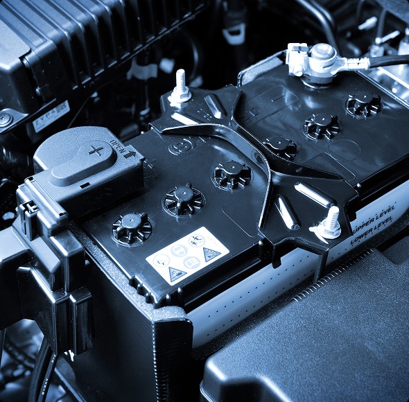 Veduta ravvicinata di una batteria per auto, con dettagli sui terminali e componenti elettrici evidenziati.