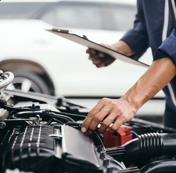 Un meccanico esperto ispeziona il motore di un'auto, mentre tiene un documento con note tecniche. La scena evidenzia l'attenzione al dettaglio nella manutenzione e riparazione dei veicoli.